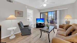 Ein modernes Wohnzimmer mit Sofa, Sessel, Couchtisch und Fernseher.