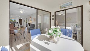 Ein modernes Wohnzimmer mit Essbereich, ausgestattet mit einem weißen Tisch, blauen Stühlen und einer dekorativen Vase.