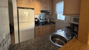 Eine kleine Küche mit Kühlschrank, Mikrowelle, Herd und Spüle.
