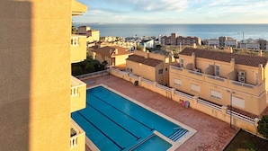 Ein Schwimmbecken mit freiem Blick auf das Meer und Gebäude im Hintergrund.