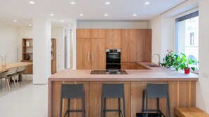 A modern kitchen with wooden cabinets, a central island with bar stools, an oven, and a sink. - Lussuosa residenza nel centro di Verona (Verona)