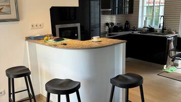 Cozinha moderna com ilha central, banquetas e janela.