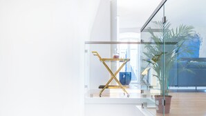 Una escalera moderna con peldaños de madera y barandilla de vidrio, que conduce a una puerta blanca.