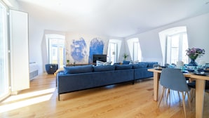 Un salón espacioso con un amplio sofá azul, una mesa de comedor con sillas y una chimenea.