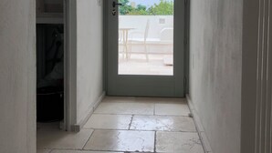 Un couloir étroit mène à une porte qui donne sur un patio extérieur.