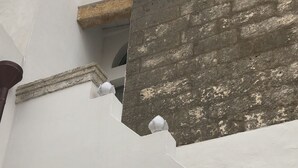 Un bâtiment à la façade blanche, avec une fenêtre visible et une partie du mur en briques.