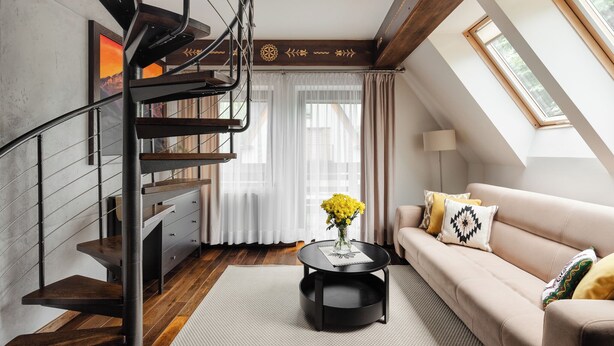 Un interior modern amb una escala, un sofà, una taula de café i una finestra.
