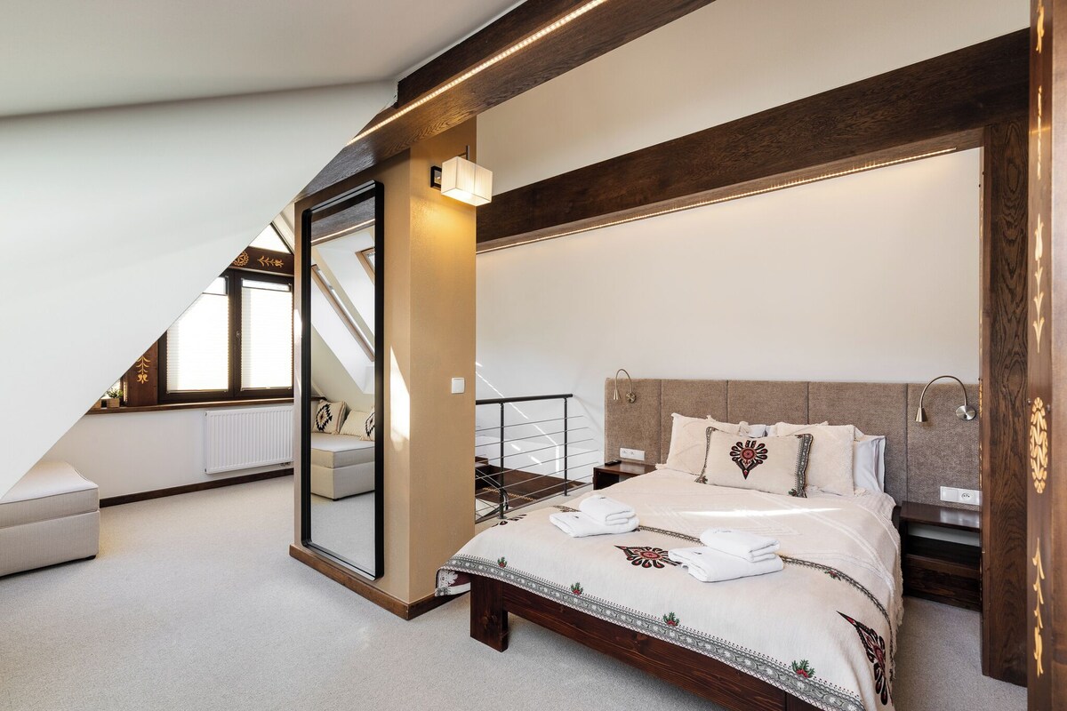 Un dormitorio con una cama grande, un espejo, una escalera y vistas al exterior.
