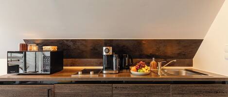 A modern kitchen with a microwave, coffee maker, and fruit bowl on the counter.