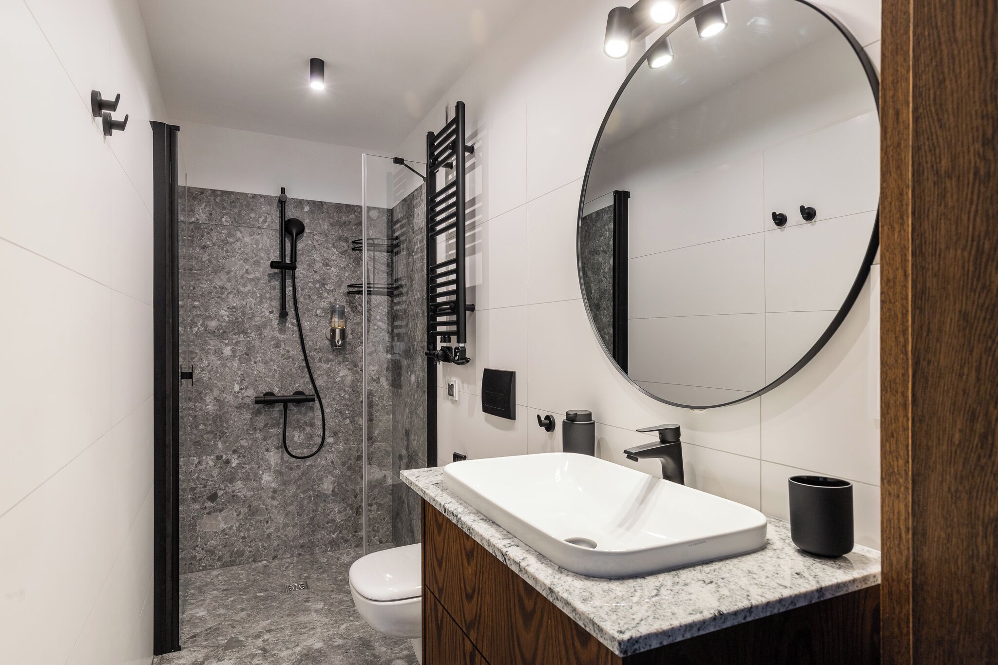 Un baño moderno con ducha, inodoro y tocador con un espejo grande.