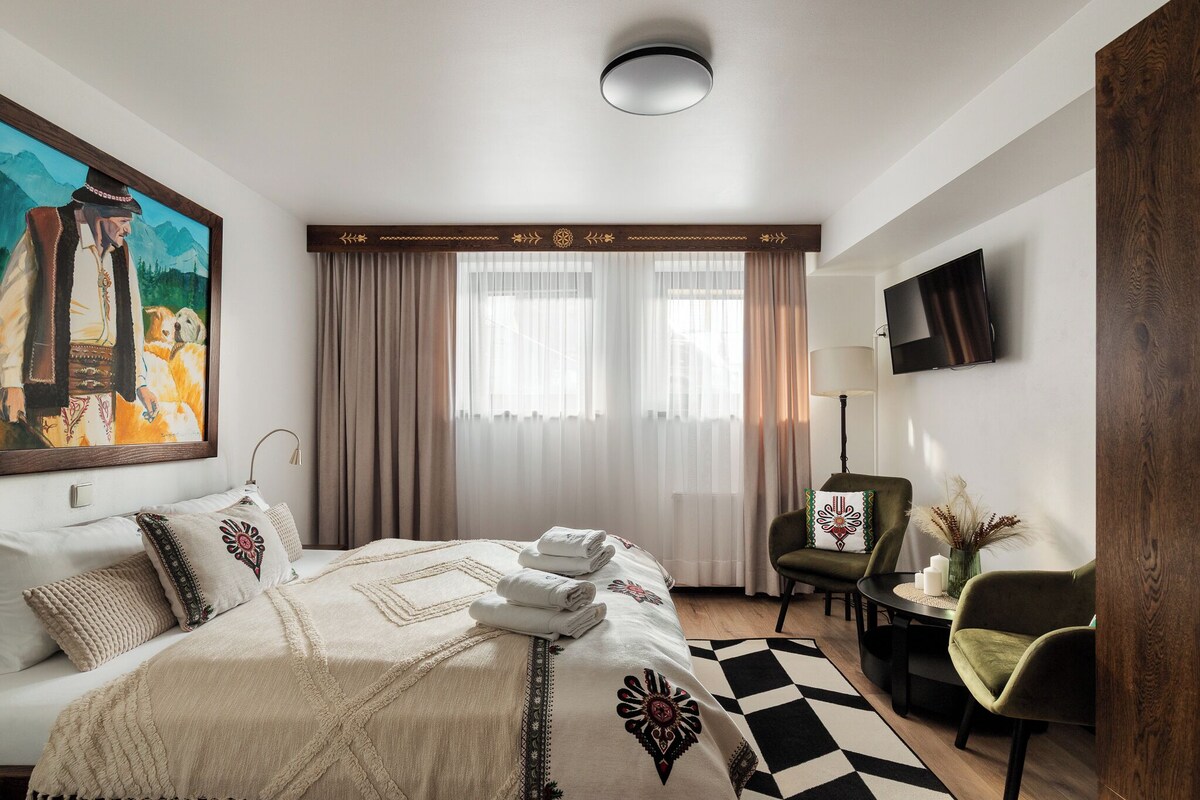 Una habitación de hotel con cama, un cuadro, televisión y un escritorio con silla.