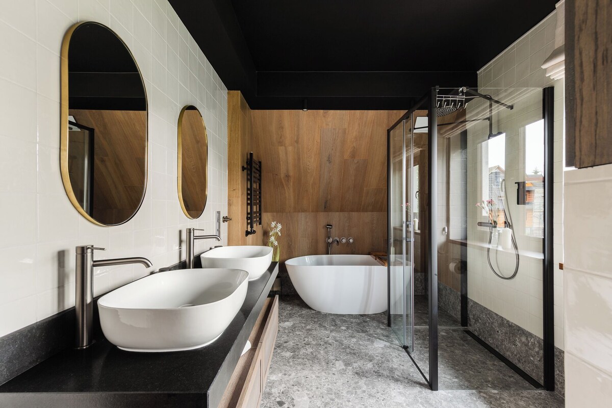 Un baño moderno con una bañera independiente grande, ducha a ras de suelo y tocador doble con dos lavamanos.
