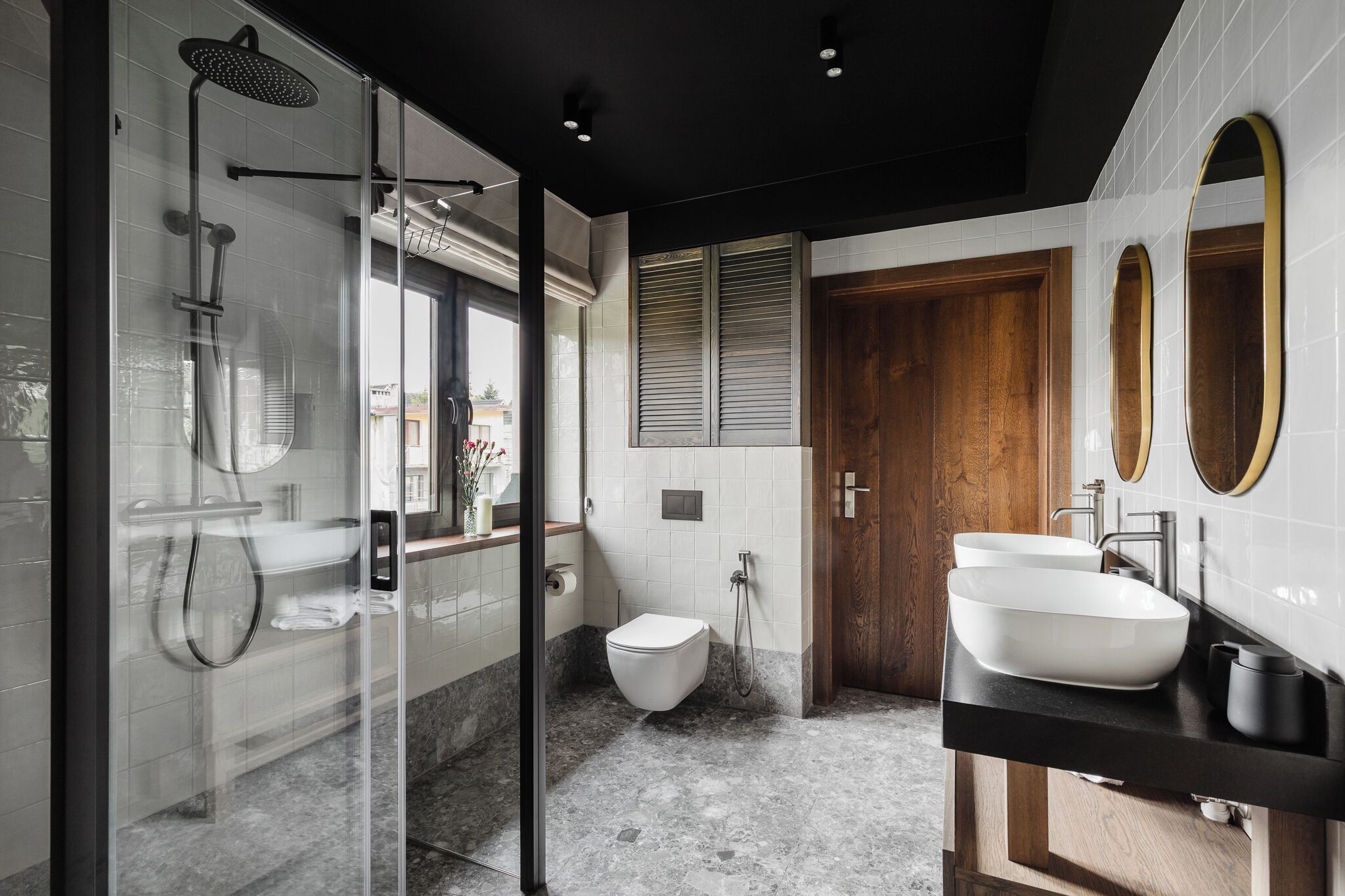 A modern bathroom with a glass shower enclosure, a toilet, and two sinks with mirrors.