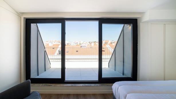 A bedroom with a large window, a bed, and a sofa. - Alcântara 2 (Lisbon)