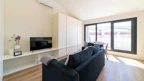 A modern living room with a dark blue sofa, a flat-screen TV, and a white cabinet. - Alcântara 2 (Lisbon)
