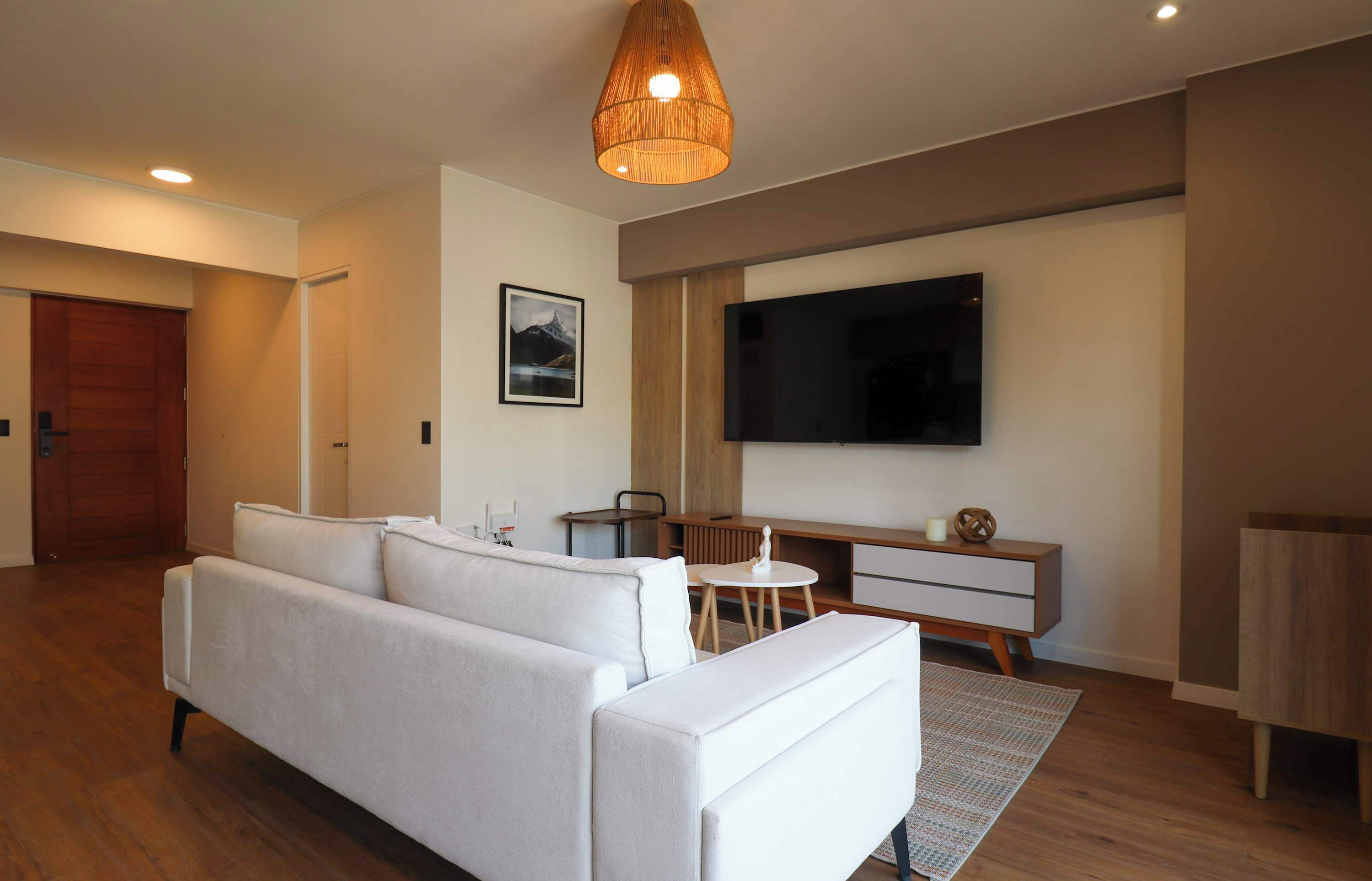 Un salon moderne avec un canapé, un téléviseur, une petite table et un meuble en bois.