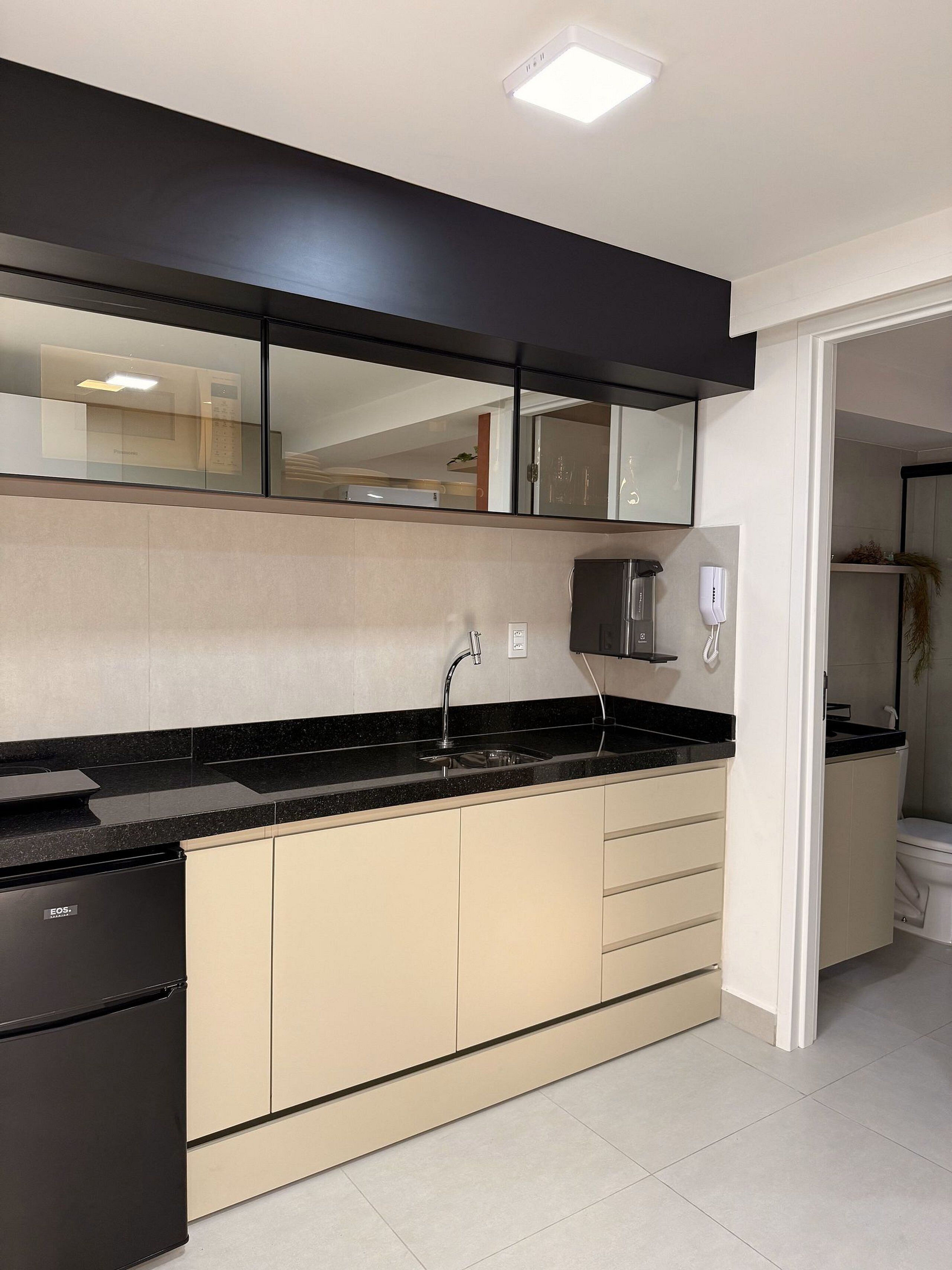 A modern kitchen with a black countertop, beige cabinets, and a built-in dishwasher.