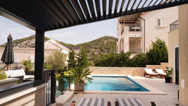 A rooftop pool area with lounge chairs, a small pool, and surrounding greenery. - royale 3 with shared pool Hvar (Hvar)