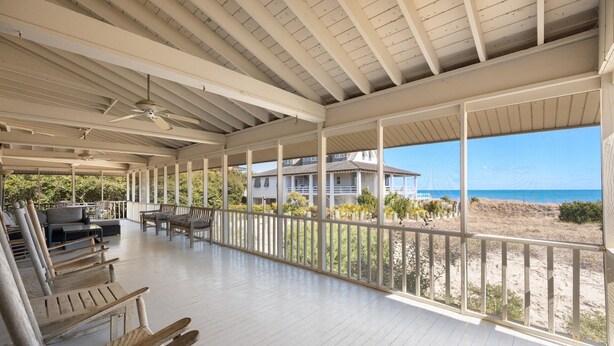 Un espacio al aire libre techado con bancos de madera y vista a la playa y al océano.