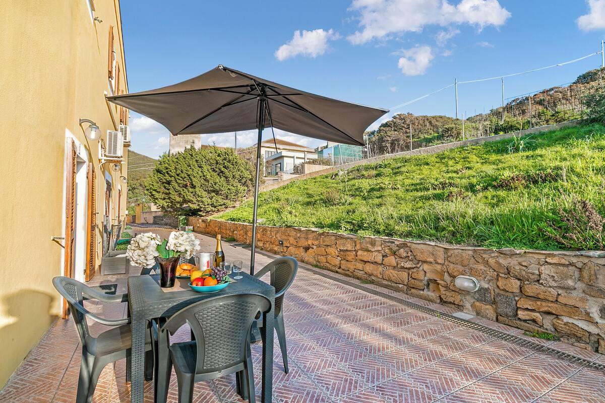 A patio with a table, chairs, and an umbrella.