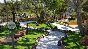 A landscaped garden with a water feature, rocks, and a pathway. - Residence Argentiera Apartments (Sassari)