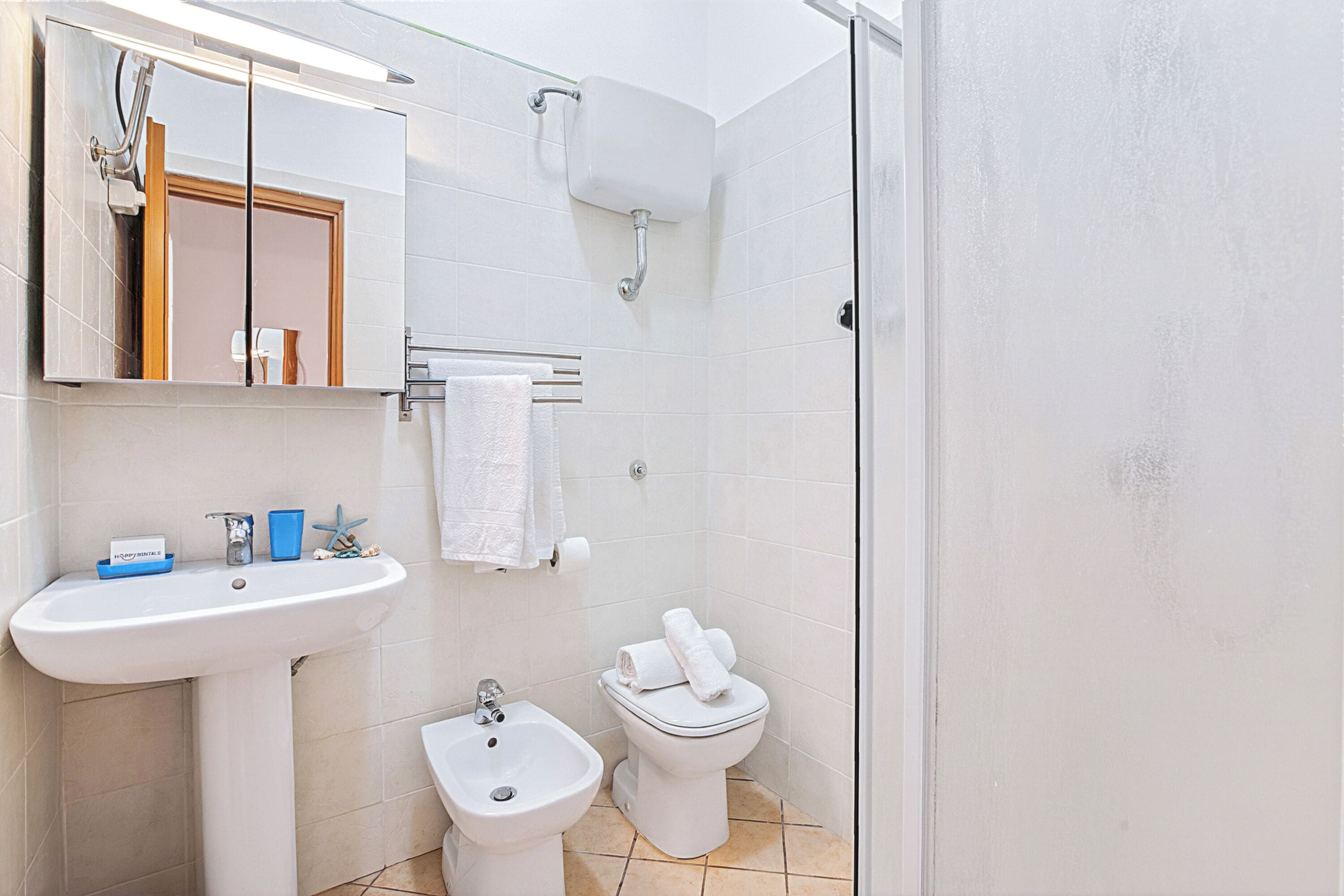 A bathroom with a sink, bidet, toilet, and a mirror.