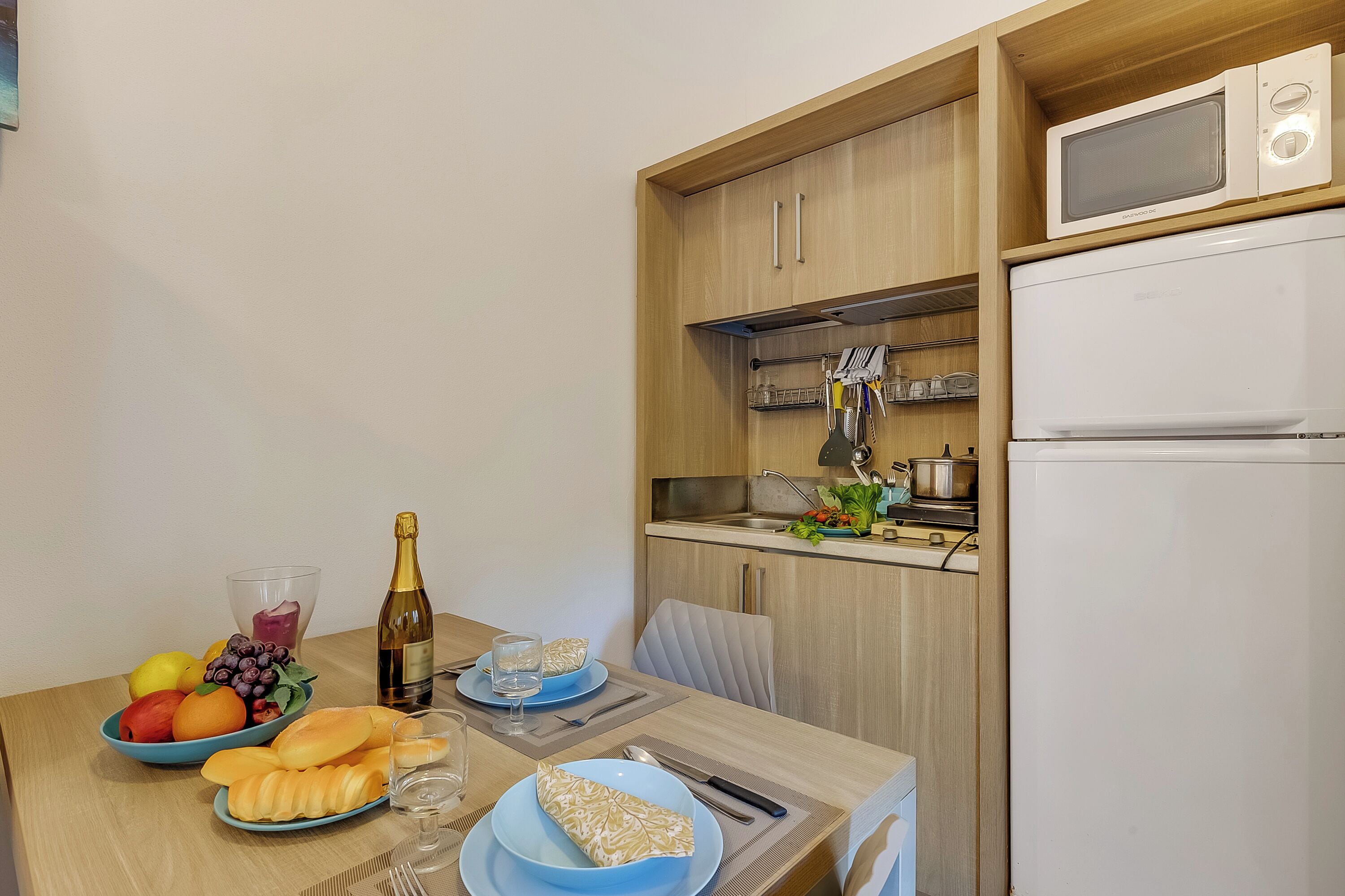 A compact kitchen with a microwave, refrigerator, and wooden cabinets.