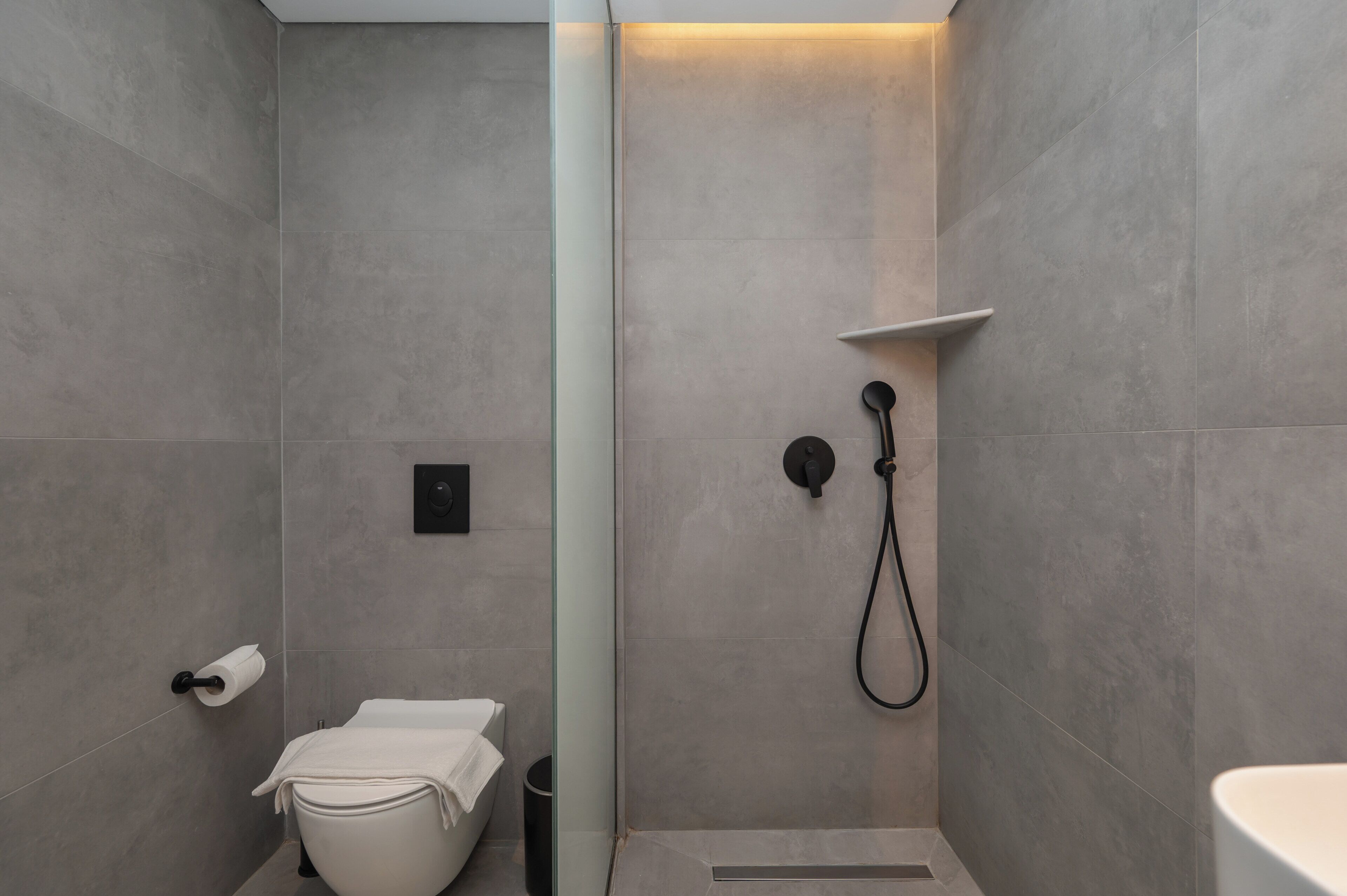 A modern bathroom with a shower, toilet, and sink.