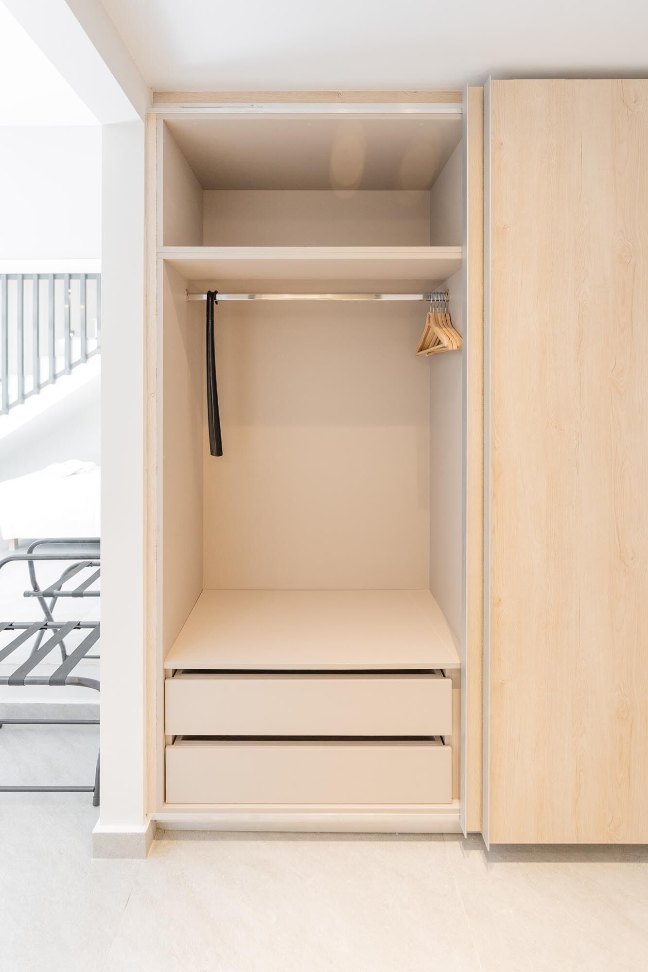 Habitación minimalista con armario empotrado, un banco y una percha.