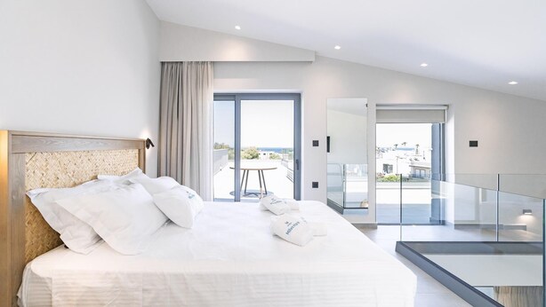 Ein modernes Hotelzimmer mit einem großen Bett, einem Balkon und Blick auf die Stadt.