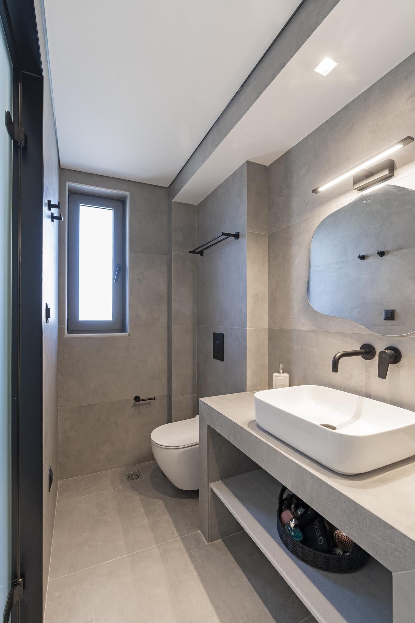 Ein modernes Badezimmer mit einem großen Spiegel, zwei Waschbecken und einer Toilette.