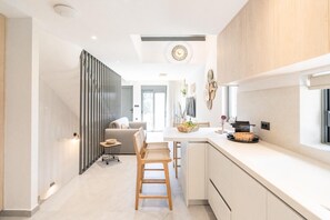 A modern kitchen with a central island, wooden chairs, and a dining table. - Milva Mare Luxury Apartments (Kos)