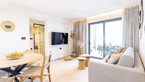 Ein modernes Wohnzimmer mit einer Couch, einem Esstisch, Stühlen und einem Fernseher.