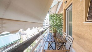 A balcony with a wooden bench, a potted plant, and a view of the street below. - Athena House Elegant Stay  By Greece Apartments (Vyronas)