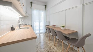 A modern kitchen with a wooden countertop, a sink, and a dining area with chairs and a table. - Athena House Elegant Stay  By Greece Apartments (Vyronas)