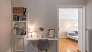 A study area with a desk, chair, bookshelf, and a view into a living room with a sofa and a mirror. - Athena House Elegant Stay  By Greece Apartments (Vyronas)