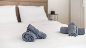 A neatly made bed with rolled towels and a wooden headboard. - Athena House Elegant Stay  By Greece Apartments (Vyronas)