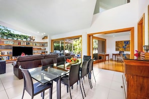 A spacious living room with a glass dining table, a comfortable sofa, and a bookshelf filled with books. - Villa Paloma (Palma de Mallorca)
