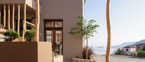 A modern outdoor area with a wicker chair, a stone planter, and a view of the sea.