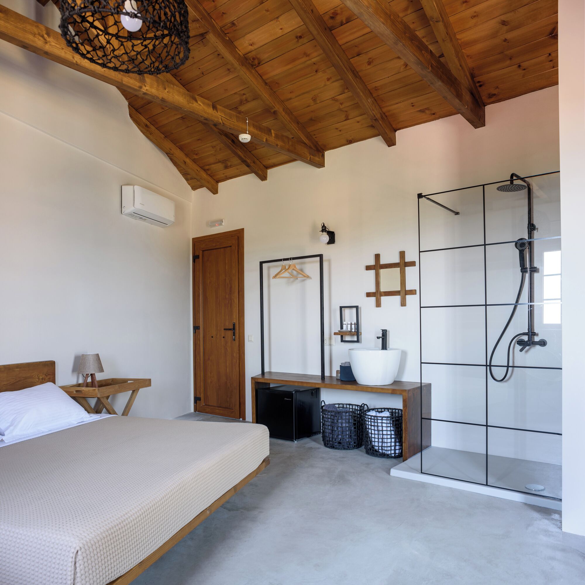 A bedroom with a bed, bedside table, and a wooden ceiling.