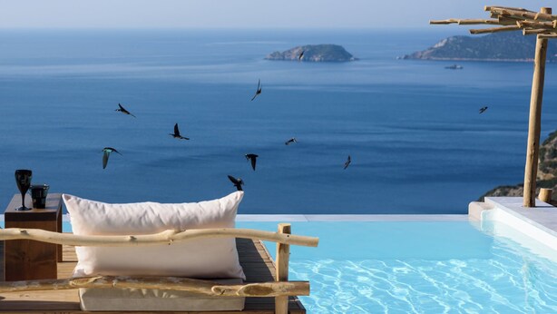A poolside lounge with a view of the sea and islands, wooden furniture, and a white cushion. - Aletri Swim Up Boutique Hotel (Alonissos)