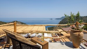 A terrace with wicker furniture, a wooden table, and a potted plant. - Aletri Swim Up Boutique Hotel (Alonissos)