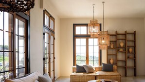 A spacious living room with a sofa, two poufs, a coffee table, and a bookshelf filled with pottery. - Aletri Swim Up Boutique Hotel (Alonissos)