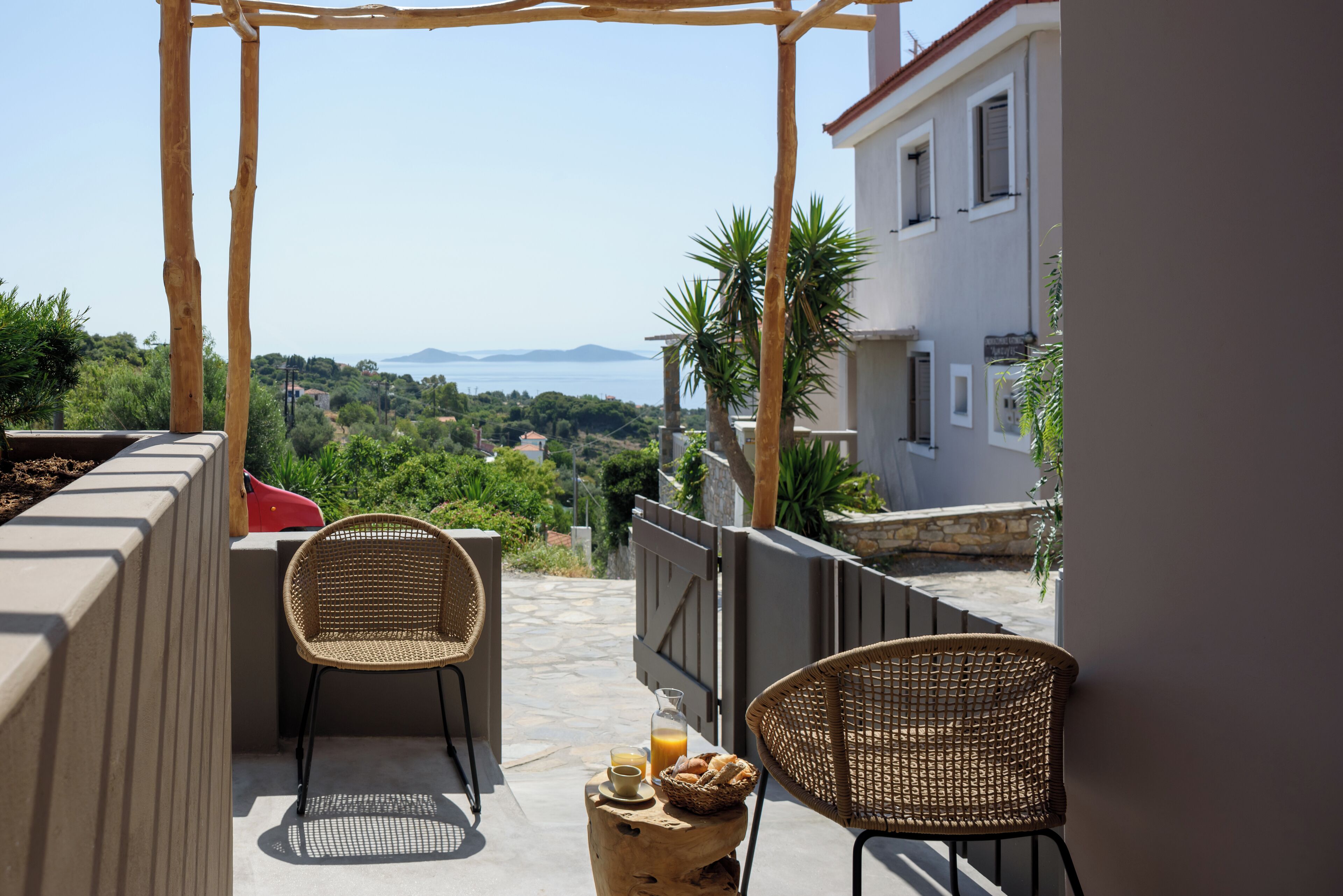A balcony with wicker chairs, a small table, and a basket of bread and juice.