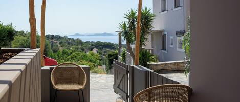 A balcony with wicker chairs, a small table, and a basket of bread and juice.