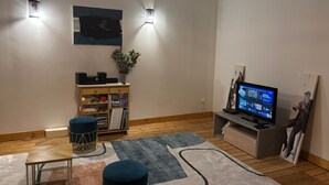Una sala de estar moderna con suelo de madera, un televisor de pantalla plana, una estantería y una planta decorativa.
