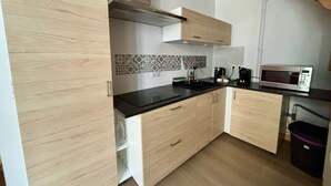Una cocina moderna con armarios de madera, encimera negra, microondas y cafetera.