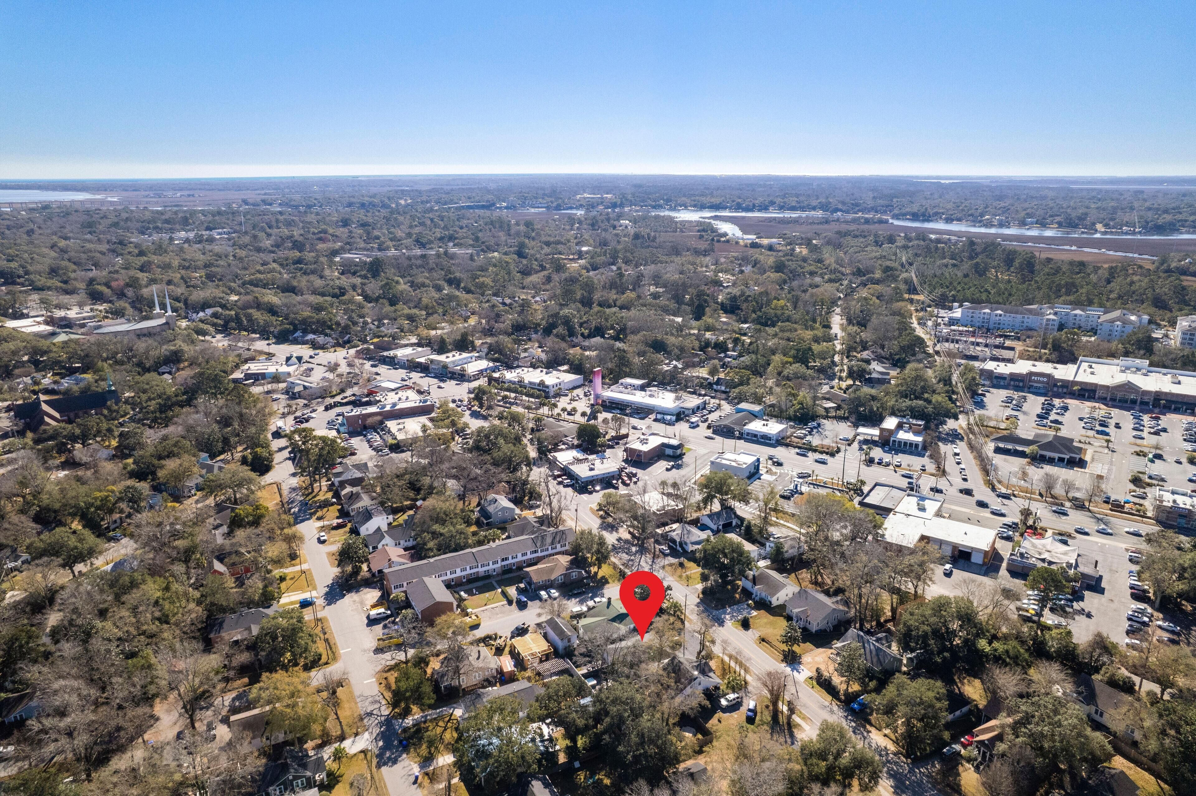 Vista aérea de una zona residencial y comercial con edificios de ambos tipos, un estacionamiento amplio y un marcador rojo destacado que indica una ubicación específica.