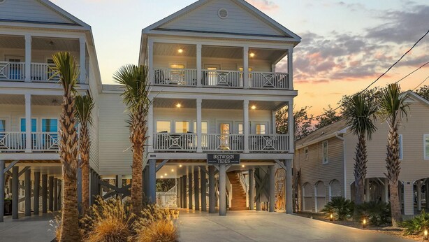 Un hôtel situé en bord de mer, avec une structure à deux étages, des balcons et une enseigne indiquant « BETWEEN TIDES ».