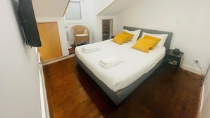 Ein Schlafzimmer mit einem Bett, einem Sessel, einem Nachttisch und einem Fenster.
